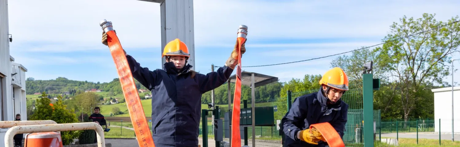 Méline et Kaméa s’entrainent à dérouler au plus vite le tuyau d’une lance à incendie.